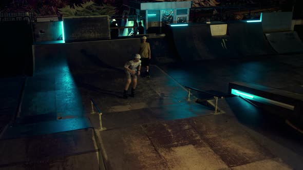 Young Teens Practicing Together on Roller Skates and Skate Board at Skate Park alt