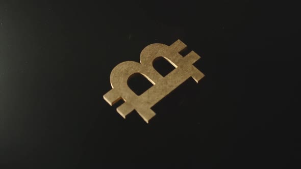 Wooden bitcoin symbol falls in darkness