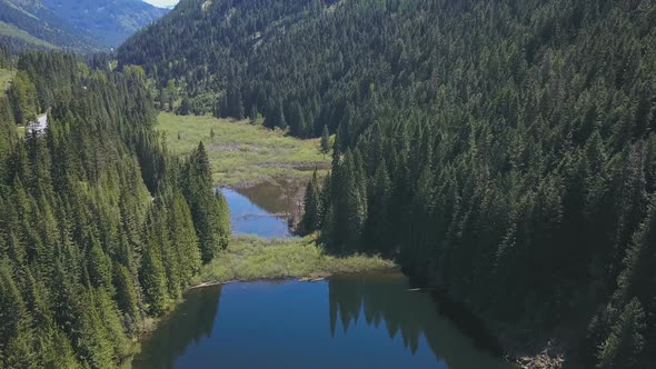 Aerial Drone Footage Of A Lake And Valley With Reflections Of Evergreen Trees On A Mountain 1