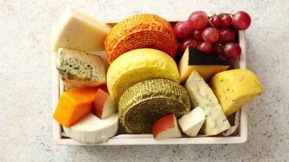 Fresh and Delicious Different Kinds of Cheeses Placed in Wooden Crate with Grapes alt