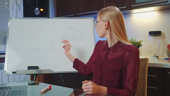 Blonde Business Woman in Eyeglasses Speaking to the Camera and Writing on Whiteboard