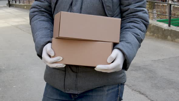 a man wearing white surgical gloves is holding a brown delivery alt