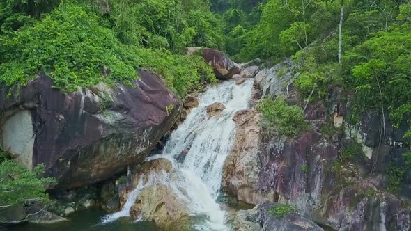Flycam Approaches Waterfall Cascade Flowing Across Boulders