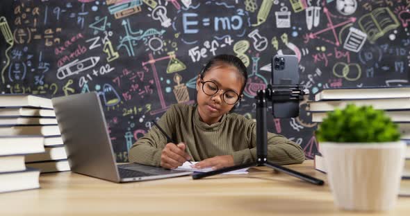 Girl kid studying online with headset in classroom alt