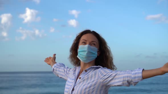 Happy woman wearing medical mask outdoor against blue sea and sky background
