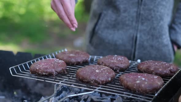 Salting Beef Burgers Cutlets Roasting on the Charcoal Barbecue Grill alt
