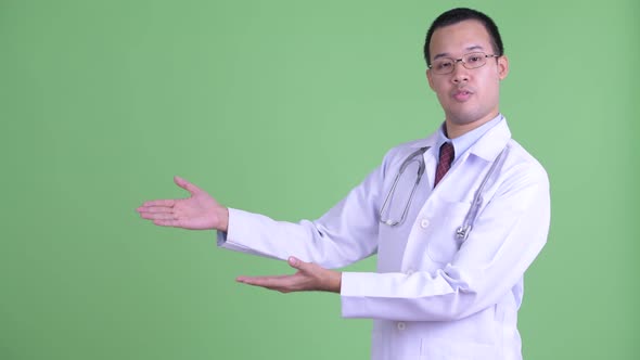Happy Asian Man Doctor Talking While Showing Something alt