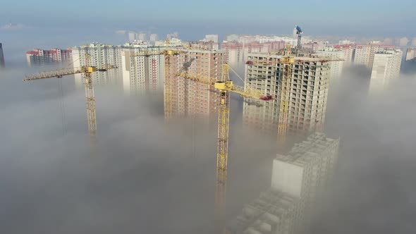 Construction Cranes Work In The Fog