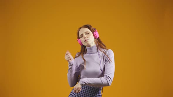 An Excited Happy Caucasian Woman Jumps Around with a Happy Expression While Listening to Music on
