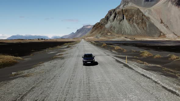 Drone Of Car Driving Along Dirt Track By Beach alt