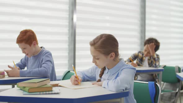 Pupils Writing in Notebooks in Classroom alt
