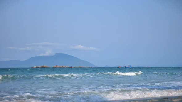 Beautiful Sea Waves with Large Sea Foam Against the Background of the Island and Two Asian Boats alt