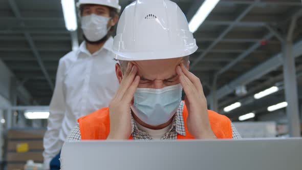 Engineer in Mask Having Headache Working at Laptop and Colleague Advising Him To Wear Eyeglasses alt