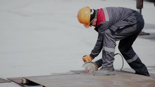 Worker Wearing Mask and Cuts Metal with Hand Disc Grinder Abrasive Saw