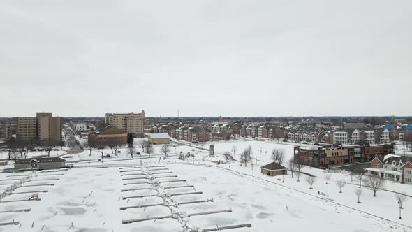 Seagulls flying over frozen marina on Lake Michigan. Large residential complex with businesses.