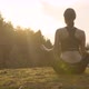 Young Woman Meditating on Sunset Background