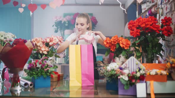 Cheerful Female Florist Packs Boxes with Plants and Gifts in Colored Paper Bags Young Woman Working alt