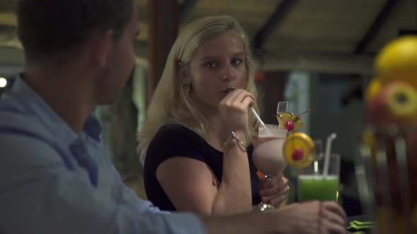 A man and woman couple have a drink at a bar at a resort alt