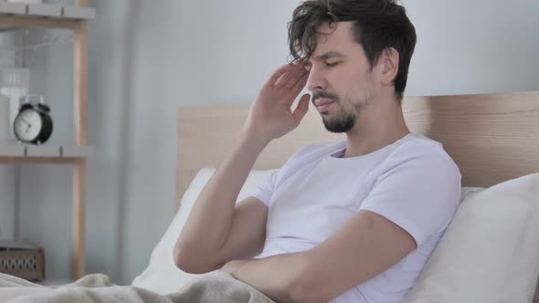 Tired Young Casual Man with Headache Sitting in Bed alt
