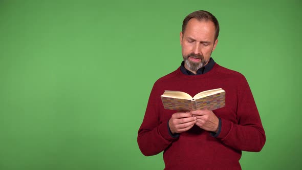 A Middleaged Handsome Caucasian Man Reads a Book  Green Screen Background