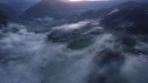 Aerial View of Fog in the Valley with Forests Meadows and Houses By the Road