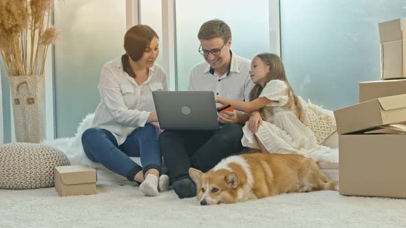 A Happy Family Uses a Laptop for Online Shopping Sitting at Home alt