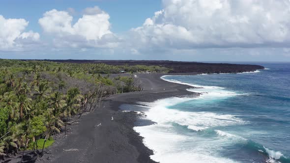 Close-up aerial shot flying over a newly formed black sand beach on the coast of the Big Island of H alt