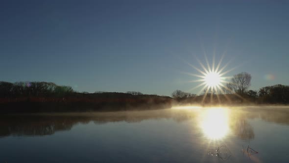 Fog Slowly Rolls Across a Lake at Sunrise Wide Shot alt