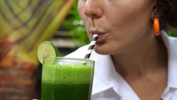Close Up of a Young Caucasian Woman Taking a Sip of Healthy Cold Pressed Green Juice alt