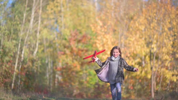 Cute Little Girl Runs and Launches Airplane Model in Autumn Park