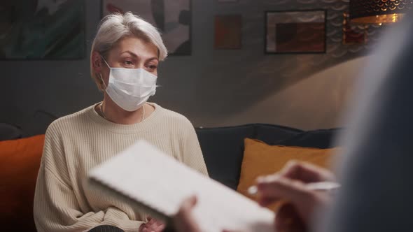 Psychologist Therapy Session Woman and Man Wearing Face Mask Sitting on the Sofa and Talking alt