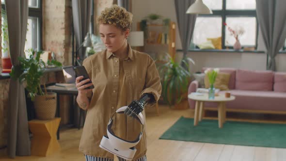 Girl with Prosthetic Arm Holding VR Headset and Using Smartphone at Home alt