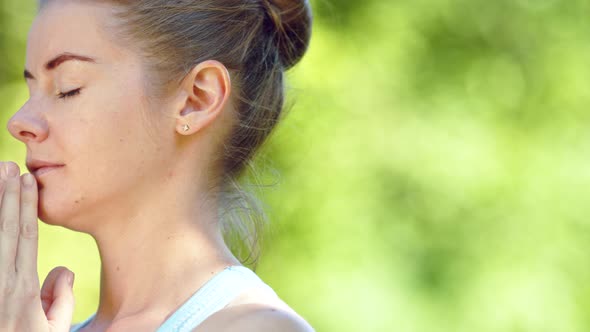 Concentrated young woman blonde meditates in yoga pose joining hands alt