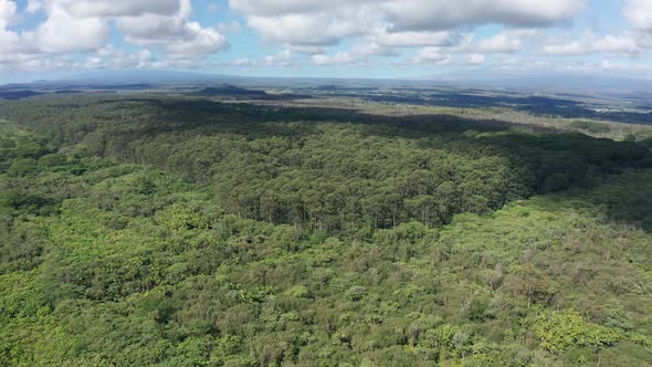 Reverse pullback aerial shot of both Mauna Loa and Mauna Kea volcanoes with clouds covering their su alt