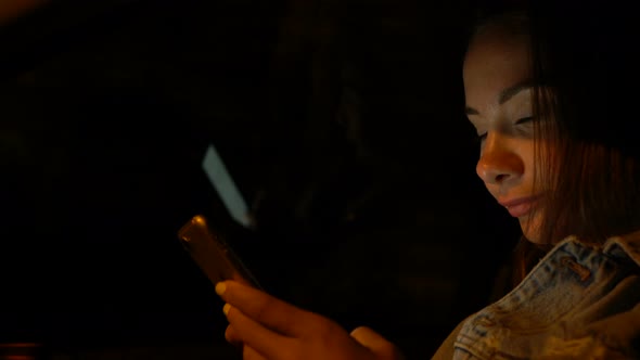 Young Woman Using Mobile Phone While Sitting in a Car at Night