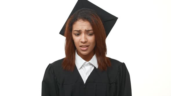 Stressed Young African American Graduate in Black Robe and Square Academical Cap Crossing Her alt