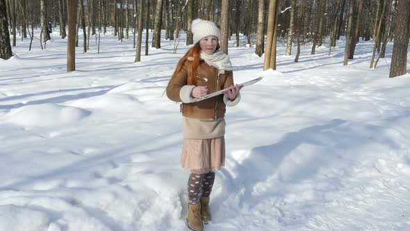 Beautiful Teen Girl Paints On Paper Outdoors at Wintertime