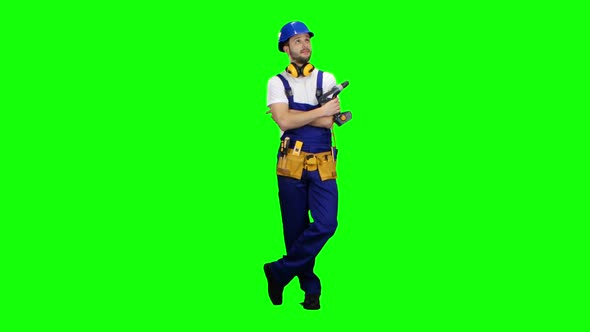 Builder Holds a Drill in His Hands and Looks Around. Green Screen alt