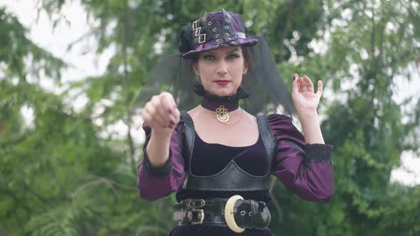 Medium Shot of Gorgeous Slim Caucasian Witch Gesturing Looking at Live Camera Zoom in alt