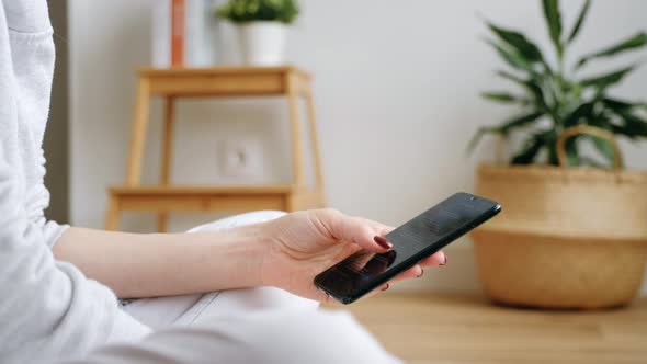 Young Female Using Smart Phones Social Media Sitting On Sofa At Home.