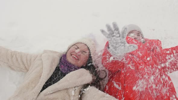 Young Woman and Teenager Girl Lie on the Snow