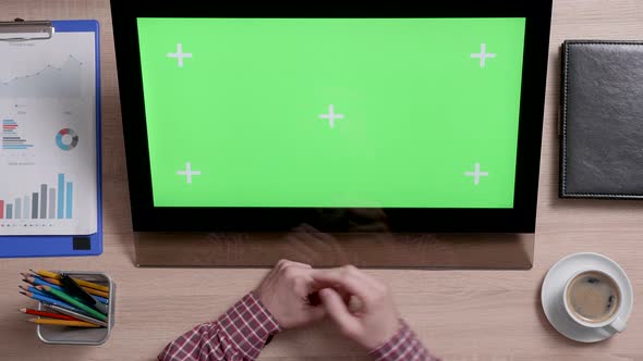 Top View of Man's Hands Scrolling Over the Bottom Edge of a Green Screen Touch Monitor alt