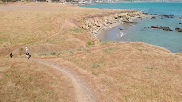 Man and Dog Walking on Hiking Trail by the Ocean