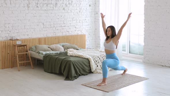 Woman Is Practicing Yoga Doing Lunge Warrior Yoga Pose on Sport Mat in Bedroom