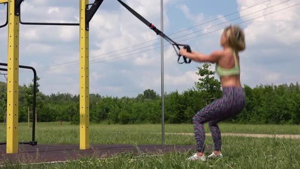 A Beautiful Fit Woman Does Assisted Squats with Jumps at an Outdoor Gym - Closeup alt