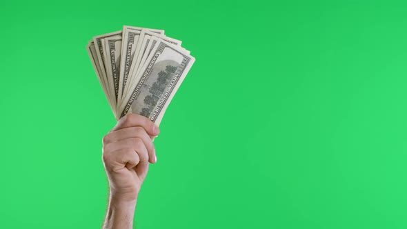 Male Hands Hold a Bundle of Dollar Bills and a Vintage Watch on a Chain Against a Green Screen alt