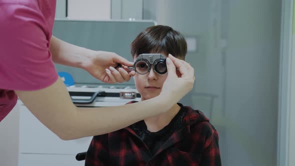 Ophthalmologist Examining Little Boy Inserting a Lens Into Lens Testing Eye Glasses Frame alt