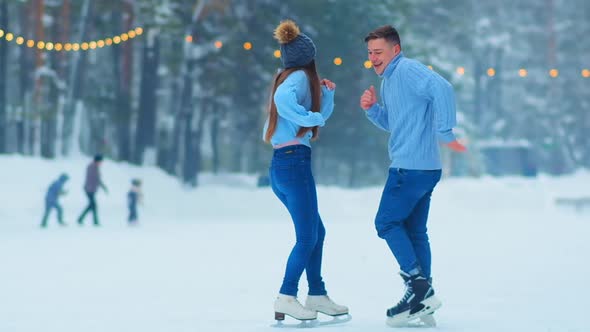 Excited Man Dances with Girlfriend on Outdoor Skating Rink