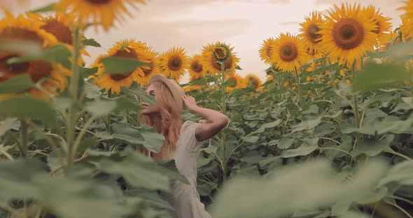 Nice Girl in a Hat Looks Into the Distance in a Field with Sunflowers