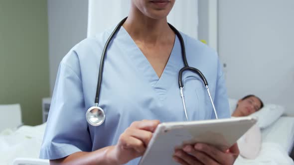 Front view of African american female doctor using digital tablet in ward at hospital 4k alt